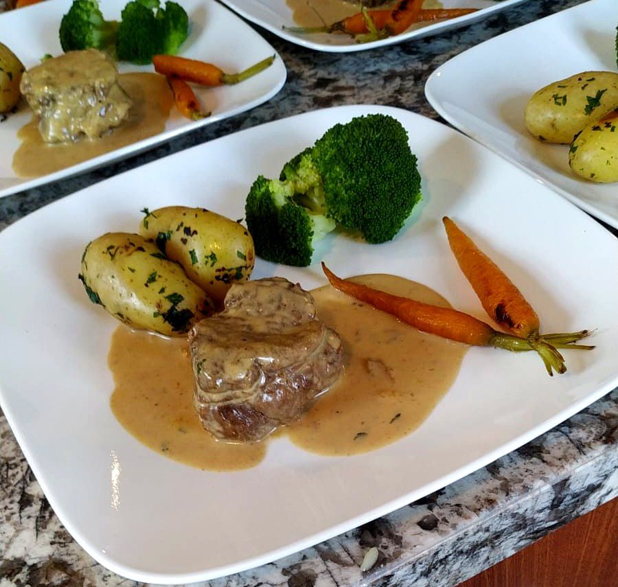 Medallón con salsa, papas baby, brócoli y zanahorias, servido en serie para un evento